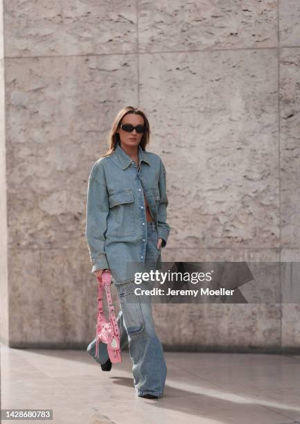 Fashion week guest seen wearing a matching amiri denim look with a balenciaga le cagole bag, outside Mame Kurogouchi during Paris Fashion Week on...