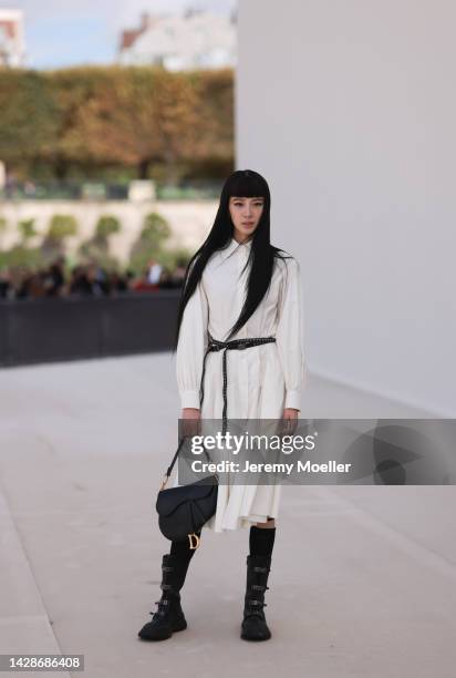 Irene Kim is seen wearing a white shirt midi dress with long sleeves from Dior, black shiny leather studded Dior belt, silver and diamond rings,...