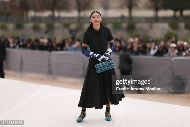 Yuwei Zhangzou is seen wearing a black long pleated dress from Dior, a black/blue/white shiny leather Dior high gloves, black with embroidered pale...