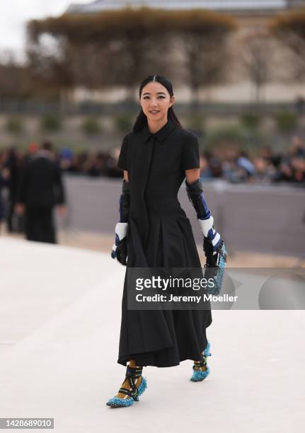 Yuwei Zhangzou is seen wearing a black long pleated dress from Dior, a black/blue/white shiny leather Dior high gloves, black with embroidered pale...