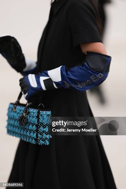 Yuwei Zhangzou is seen wearing a black long pleated dress from Dior, a black/blue/white shiny leather Dior high gloves and a black with embroidered...