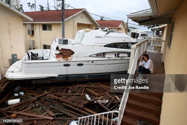 Brenda Brennan sits next to a boat that pushed against her apartment when Hurricane Ian passed through the area on September 29, 2022 in Fort Myers,...