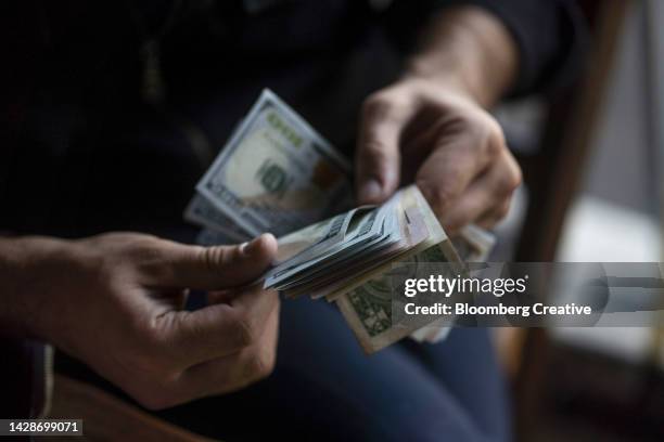 a person counting us dollar bills - human prosperity stock pictures, royalty-free photos & images