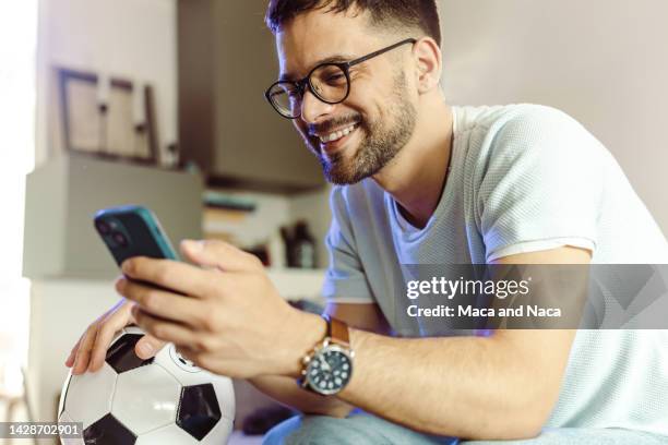 a young man holding mobile phone and betting online - finals game one stock pictures, royalty-free photos & images