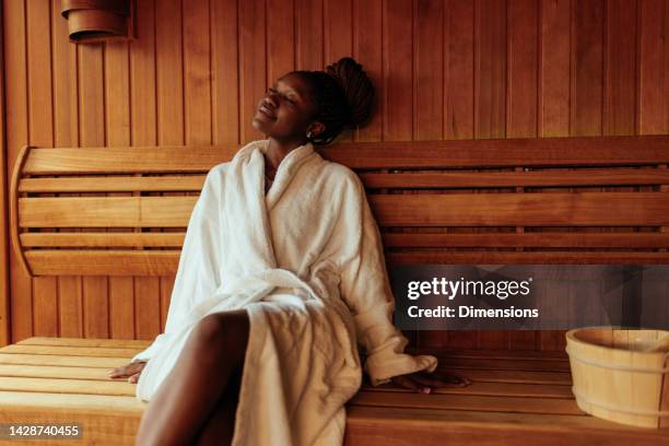 joven negra disfrutando en la sauna. - bathrobe fotografías e imágenes de stock