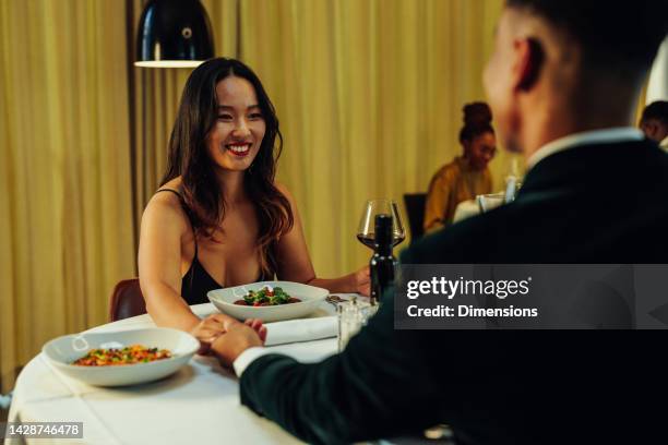 romantic multiracial couple at dinner. - couple dinner date stock pictures, royalty-free photos & images