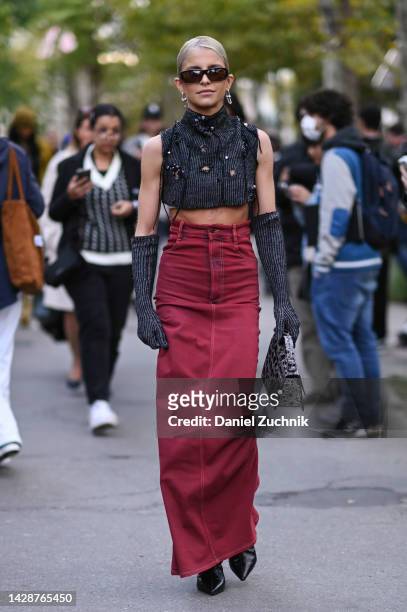 Caroline Daur is seen wearing a distressed Acne top and red Acne jean skirt, knit sleeves and Acne snakeskin bag with brown sunglasses outside the...