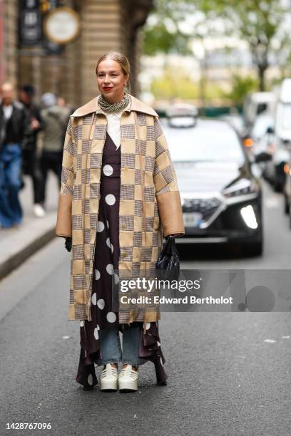 Guest wears gold earrings, a large crystals necklace, a white latte shirt, a beige with brown and white houndstooth print pattern embroidered yoke...