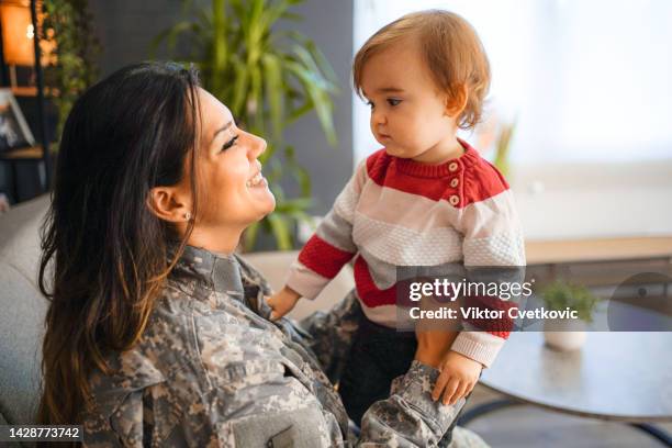 female soldier playing with her daughter after arriving home - veteran entrepreneur stock pictures, royalty-free photos & images
