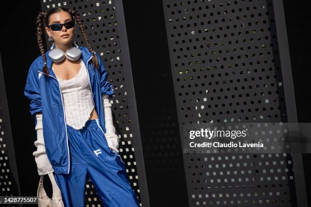 Karina Nigay is seen wearing a blue track suit, a white top and Apple airpods max outside the Gucci show during the Milan Fashion Week - Womenswear...