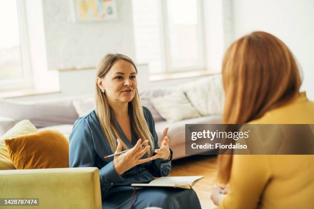 two women in armchairs are sitting and talking - psicoterapeuta foto e immagini stock