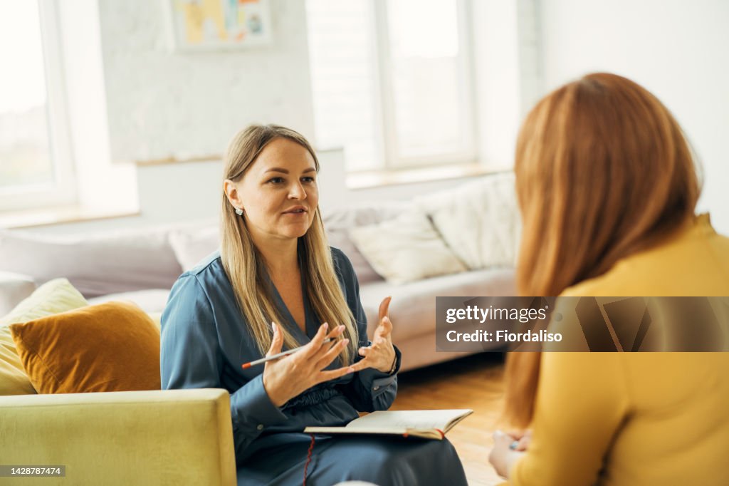Two women in armchairs are sitting and talking
