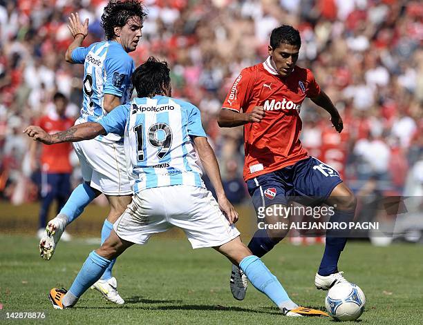 Independiente's midfielder Fernando Godoy controls the ball past Racing Club's midfielder Lucas Castro and forward Gabriel Hauche, during their...
