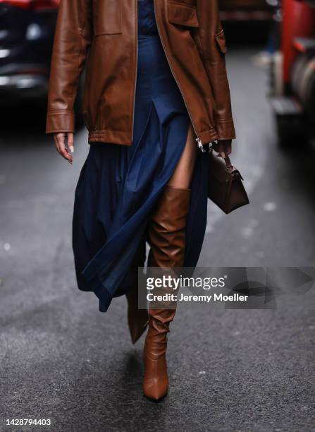 Brittany Xavier seen wearing a blue dress with a brown leather jacket and brown overknee boots, outside Carolina Herrera during new york fashion week...