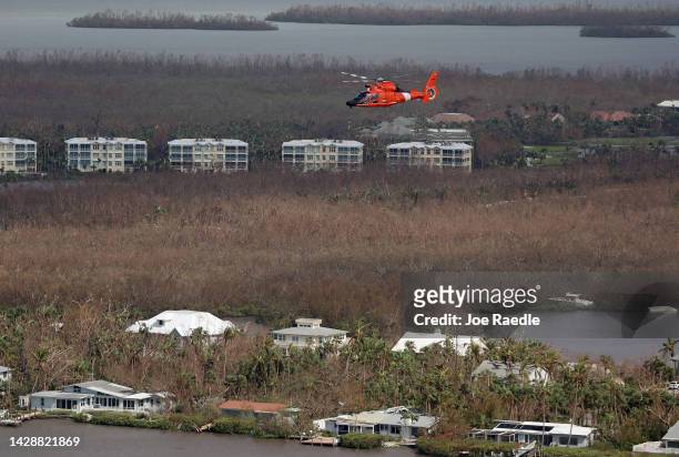 In this aerial view, a Coast Guard helicopter flies over the island as search and rescue efforts continue after Hurricane Ian passed through the area...