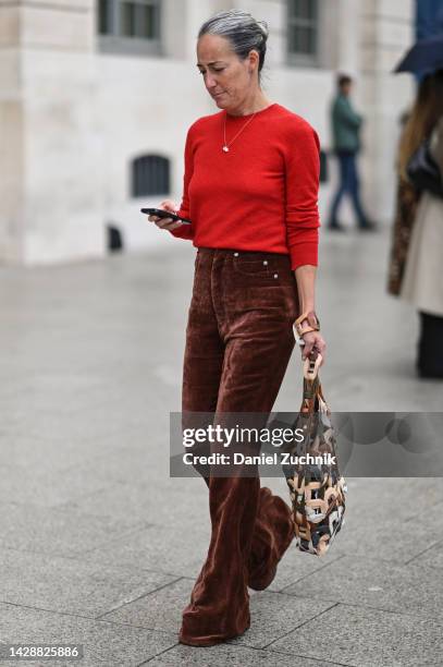 Guest is seen wearing a red sweater, brown pants and leather open bag outside the Chloe show during Paris Fashion Week S/S 2023 on September 29, 2022...