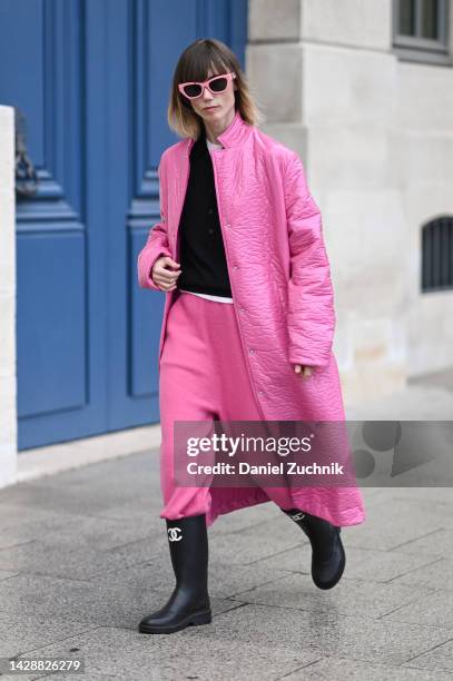 Anya Ziourova is seen wearing a pink coat, black sweater, pink pants and Chanel boots with pink sunglasses outside the Chloe show during Paris...