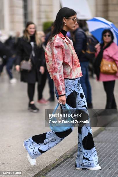 Melanie Darmon is seen wearing a Barbara Bui red and white jacket, blue and black jeans and a light blue bag outside the Chloe show during Paris...