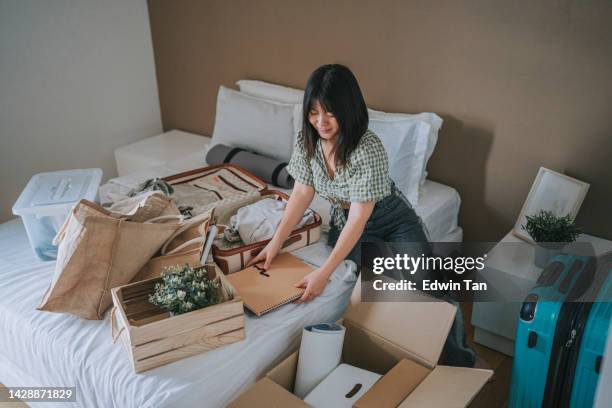 asiatische chinesische junge frau beim auspacken im studentenwohnheim - entrümpeln stock-fotos und bilder