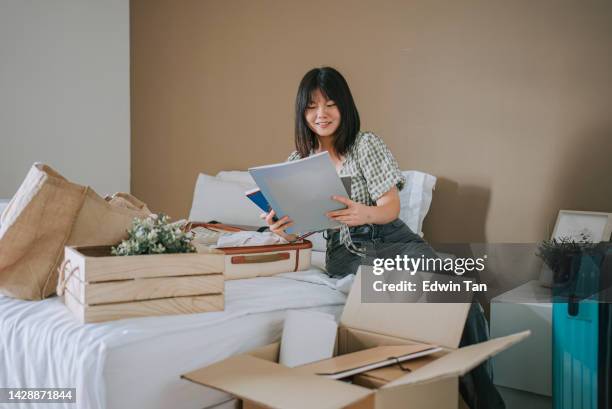 asiatische chinesische junge frau beim auspacken im studentenwohnheim - entrümpeln stock-fotos und bilder