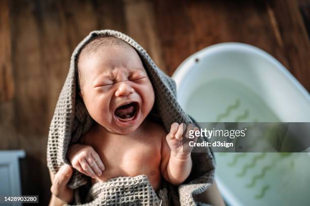 high angle shot of a loving asian mother holding crying newborn baby wrapped in a towel, drying baby girl after a fresh bath. new life. love and care concept - son massage mom imagens e fotografias de stock