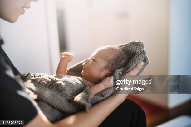 cropped shot of a loving asian mother holding newborn baby wrapped in a towel, drying baby girl after a fresh bath. new life. love and care concept - asian massage girl stock-fotos und bilder