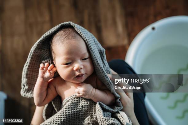 high angle shot of a loving asian mother holding newborn baby wrapped in a towel, drying baby girl after a fresh bath. new life. love and care concept - massage boy bildbanksfoton och bilder