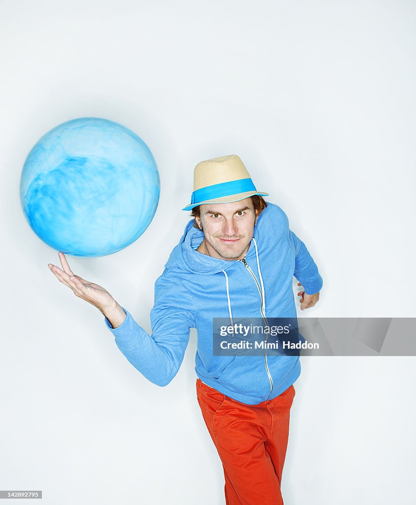 Hip Young Man Balancing Blue Ball on Fingertip