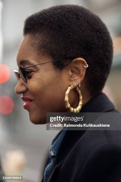 Tamu McPherson denim shirt, long black coat and golden earings outside the Gauchere show during Paris Fashion Week S/S 2023 on September 29, 2022 in...