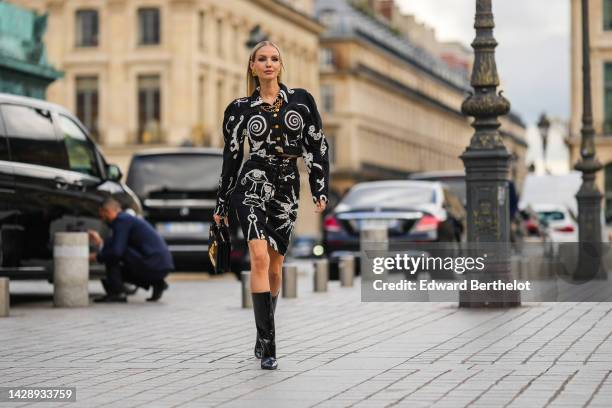 Leonie Hanne wears gold large earrings from Schiaparelli, a gold large chain necklace, a black and white print pattern with embroidered shell seams...