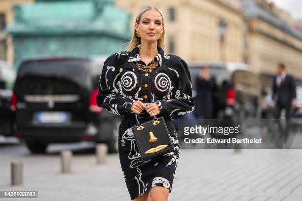 Leonie Hanne wears gold large earrings from Schiaparelli, a gold large chain necklace, a black and white print pattern with embroidered shell seams...