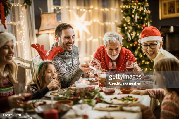 feliz familia extendida teniendo el almuerzo de año nuevo en la mesa del comedor. - christmas family fotografías e imágenes de stock