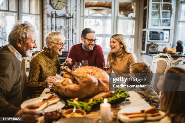 happy extended family talking during thanksgiving meal at dining table. - happy thanksgiving stockfoto's en -beelden