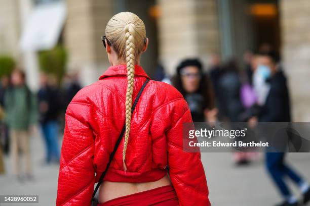 Thora Valdimars wears a red shiny varnished leather crocodile print pattern zipper / cropped jacket, a gray denim crossbody bag from Saint Laurent,...