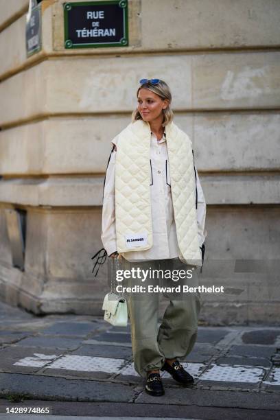 Guest wears black sunglasses, a gold necklace, a pale purple tank-top, a white latte oversized shirt with black lace sleeves and borders shirt, a...