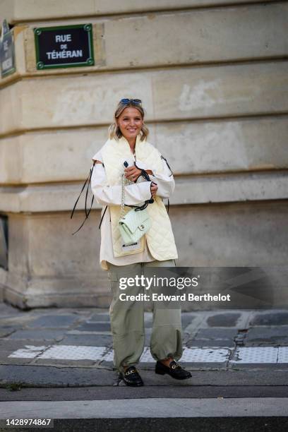 Guest wears black sunglasses, a gold necklace, a pale purple tank-top, a white latte oversized shirt with black lace sleeves and borders shirt, a...