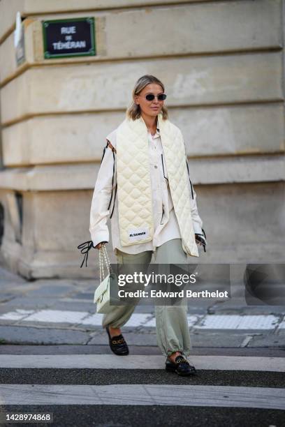 Guest wears black sunglasses, a gold necklace, a pale purple tank-top, a white latte oversized shirt with black lace sleeves and borders shirt, a...