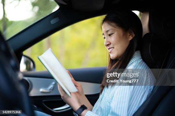 車の中で読書をするアジアの若い女性 - learning to drive ストックフォトと画像