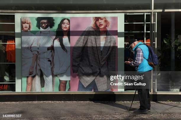 An elderly man looks at his smartphone outside a clothing store on September 30, 2022 in Berlin, Germany. Inflation in Germany reaches 10.9% in...