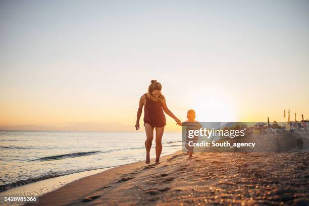 a mother and her child walking on the beach - golden hour beach stock pictures, royalty-free photos & images
