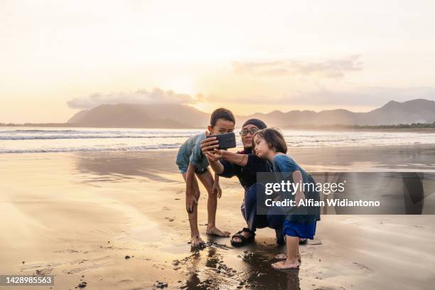 playing in the beach during sunset - muslim woman beach - fotografias e filmes do acervo