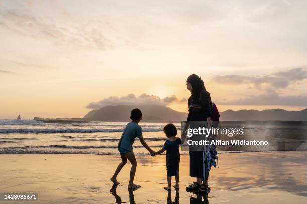 playing in the beach during sunset - muslim woman beach stock-fotos und bilder