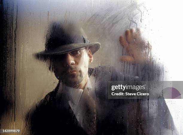 man in a hat looking out a steamy window - detetive imagens e fotografias de stock