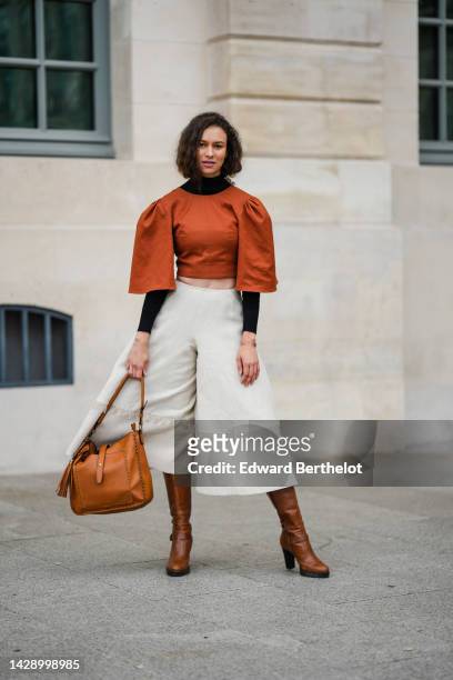 Guest wears a black turtleneck / long sleeves cropped top, a camel puffy short sleeves cropped blouse, high waist white latte linen oversized wide...