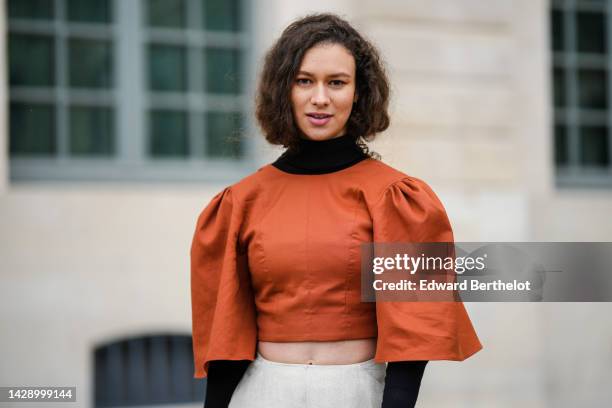 Guest wears a black turtleneck / long sleeves cropped top, a camel puffy short sleeves cropped blouse, high waist white latte linen oversized wide...