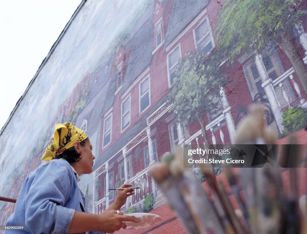 A woman painting a picture of a house