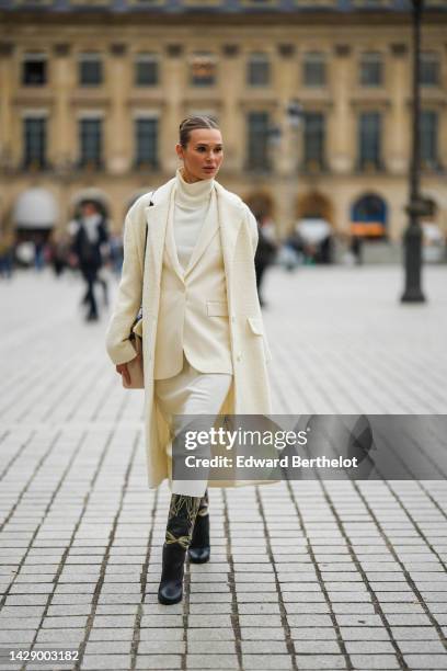 Guest wears a white latte turtleneck long wool dress, a white latte blazer jacket, a white latte long fluffy coat, a black shiny leather shoulder...