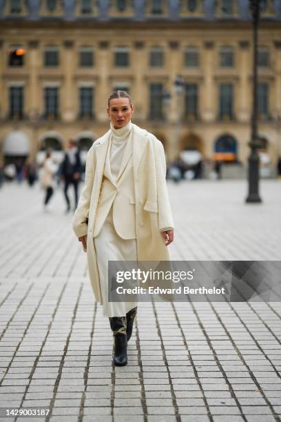 Guest wears a white latte turtleneck long wool dress, a white latte blazer jacket, a white latte long fluffy coat, a black shiny leather shoulder...