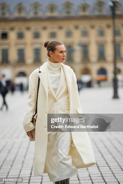 Guest wears a white latte turtleneck long wool dress, a white latte blazer jacket, a white latte long fluffy coat, a black shiny leather shoulder...