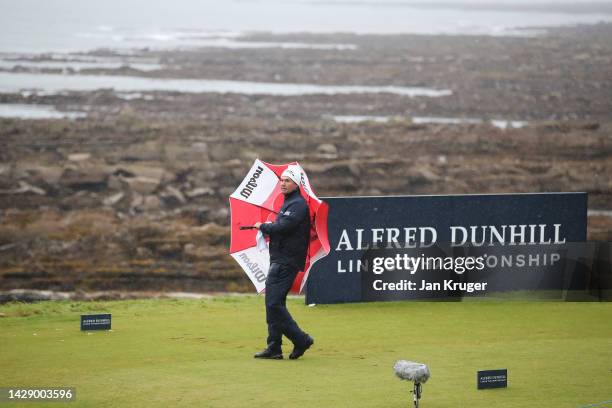 Padraig Harrington of Ireland looks on from the 15th tee holding an umbrella in the rain on Day Two of the Alfred Dunhill Links Championship at...